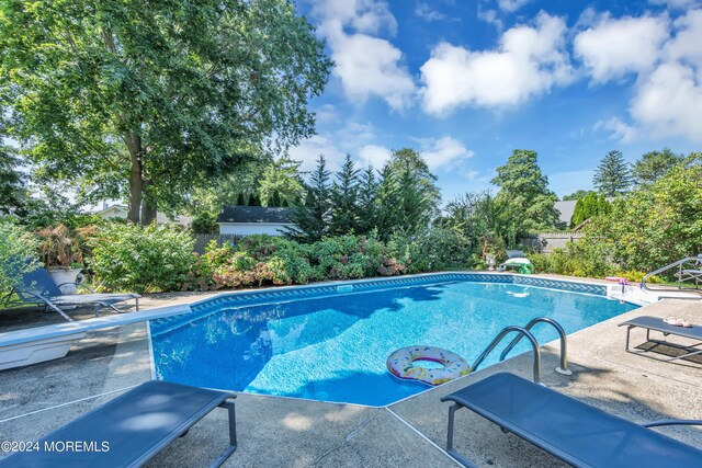 view of pool featuring a diving board and a patio