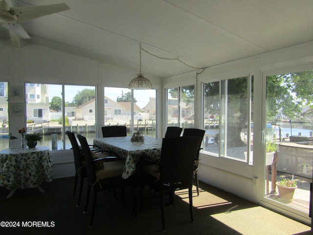 sunroom featuring ceiling fan, lofted ceiling, a water view, and a healthy amount of sunlight