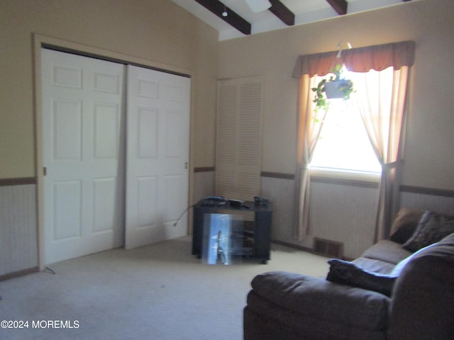 living area featuring beamed ceiling, plenty of natural light, and carpet floors