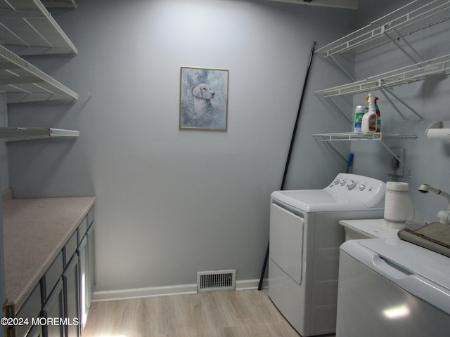 clothes washing area with washer and clothes dryer and light hardwood / wood-style flooring