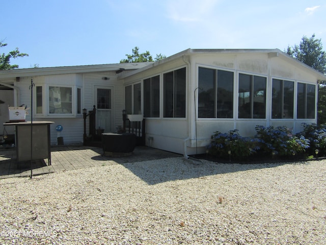 rear view of property featuring a sunroom and a patio area