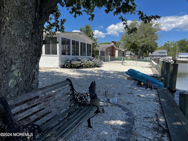 view of yard with a sunroom, a water view, and a boat dock