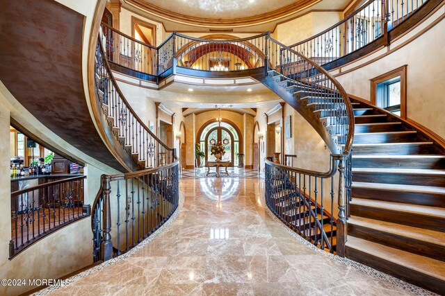 entrance foyer featuring crown molding, an inviting chandelier, and a high ceiling