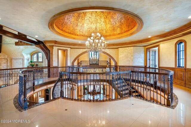 interior space featuring a tray ceiling, an inviting chandelier, crown molding, and tile patterned floors