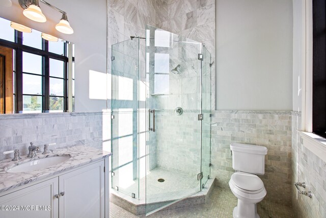 bathroom featuring tile patterned floors, walk in shower, toilet, tile walls, and vanity