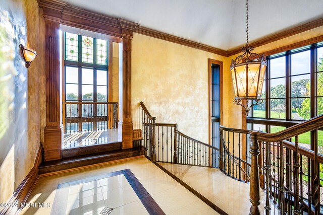 corridor with crown molding, a notable chandelier, and light tile patterned floors