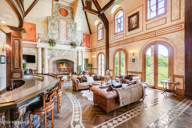 living room with a fireplace, a high ceiling, decorative columns, french doors, and dark parquet floors