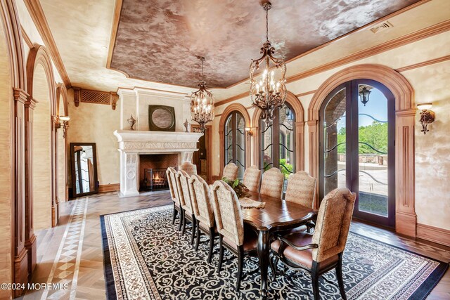 dining room with a fireplace, a raised ceiling, a notable chandelier, crown molding, and french doors