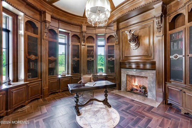 home office with a high end fireplace, a notable chandelier, crown molding, a high ceiling, and dark parquet flooring