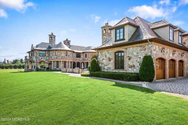 rear view of property featuring a garage and a lawn