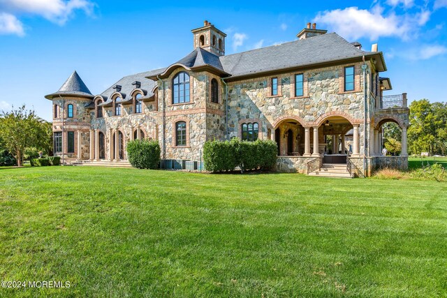 back of house featuring a balcony and a lawn