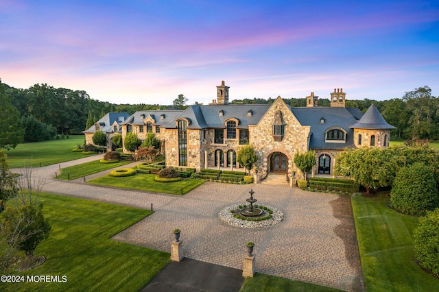 86 Montrose Rd, Colts Neck, NJ 07722 - french country style house featuring curved driveway, a high end roof, stone siding, a front lawn, and a chimney