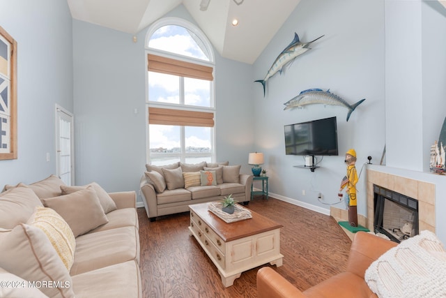 living area featuring high vaulted ceiling, wood finished floors, a tile fireplace, and a wealth of natural light