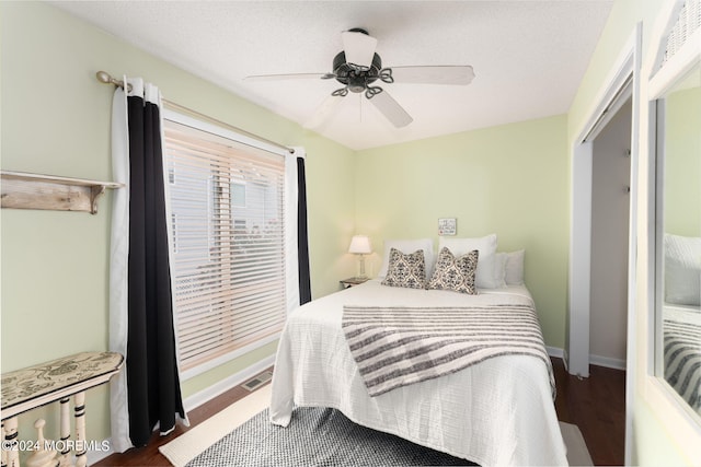 bedroom featuring baseboards, ceiling fan, visible vents, and wood finished floors