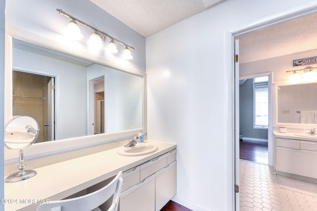 bathroom featuring tile patterned flooring, baseboards, a textured ceiling, and vanity