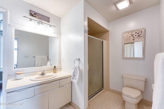 bathroom with toilet, a stall shower, a textured ceiling, vanity, and tile patterned flooring