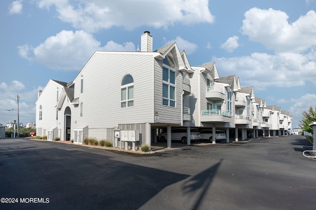 view of building exterior featuring covered parking and a residential view