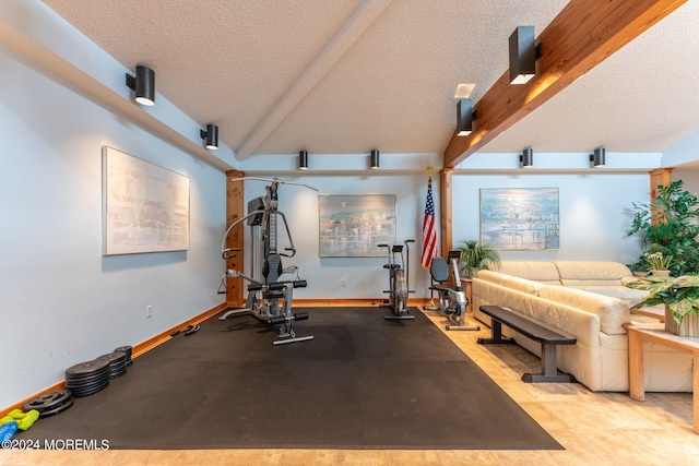 exercise room with a textured ceiling, vaulted ceiling, and baseboards