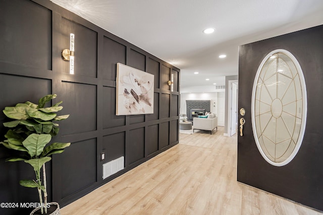 entryway with a fireplace and light wood-type flooring