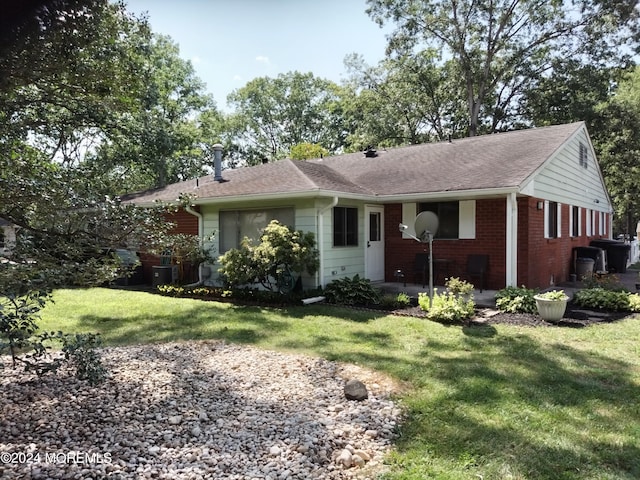 ranch-style house featuring roof with shingles, a front lawn, and brick siding