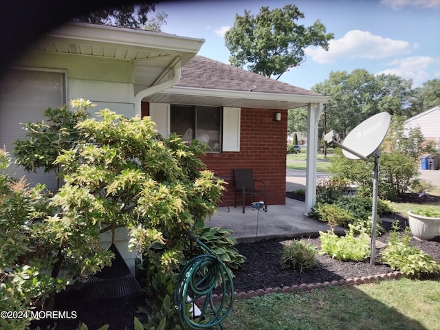 view of property exterior with brick siding and roof with shingles