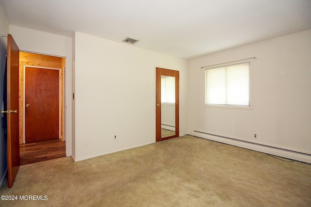 carpeted empty room featuring visible vents and baseboard heating