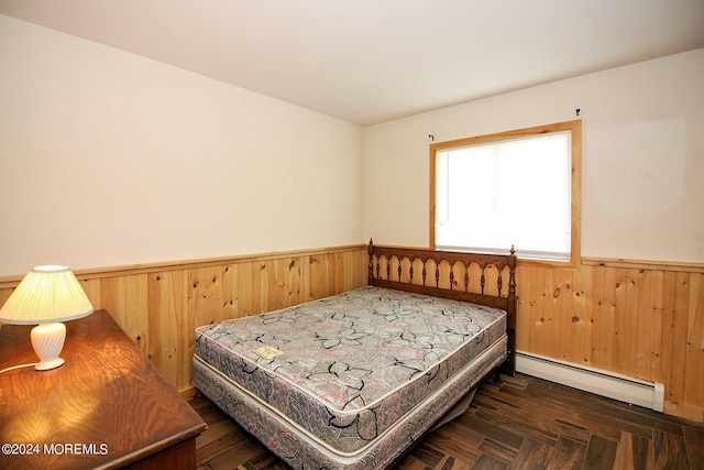 bedroom featuring baseboard heating, wainscoting, and wooden walls