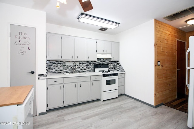 kitchen with tasteful backsplash, white appliances, a sink, and under cabinet range hood