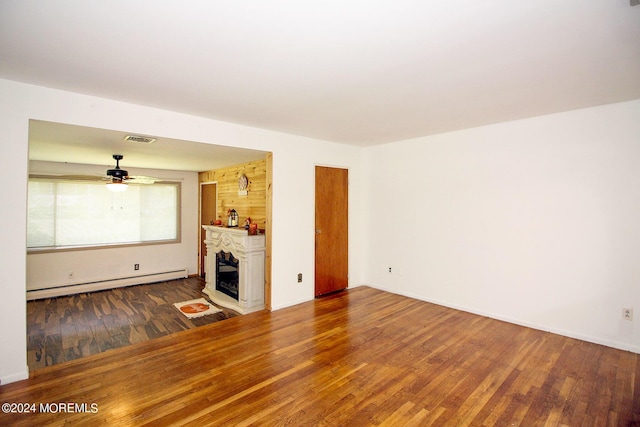 unfurnished living room with a baseboard heating unit, a fireplace, wood finished floors, and visible vents