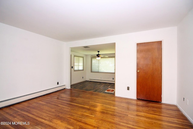 unfurnished room with baseboard heating, a baseboard radiator, wood finished floors, and baseboards