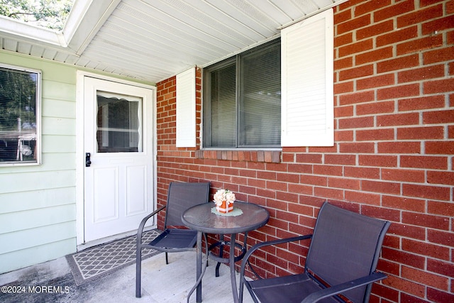 entrance to property featuring a porch and brick siding