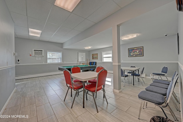 dining room featuring a baseboard radiator, ornate columns, an AC wall unit, a drop ceiling, and baseboards