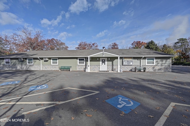 view of front of property with uncovered parking, stone siding, and an AC wall unit