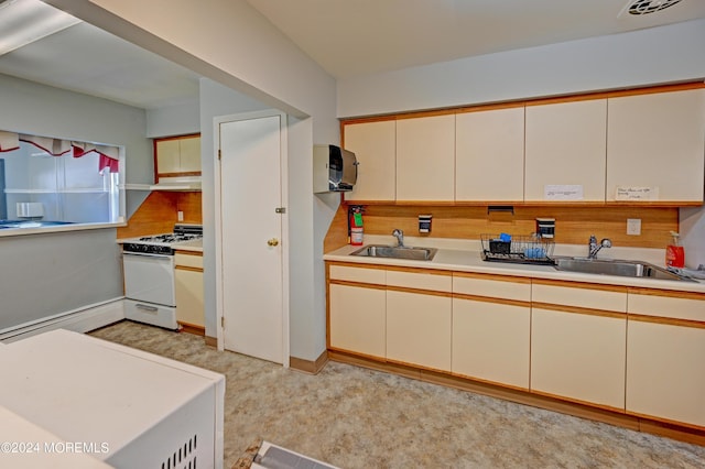 kitchen featuring white gas stove, cream cabinets, a sink, and light countertops