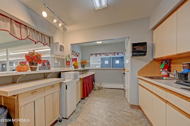 kitchen featuring white microwave, a baseboard heating unit, a sink, light countertops, and rail lighting