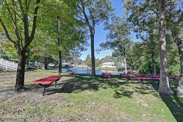 view of property's community with a water view, fence, and a lawn