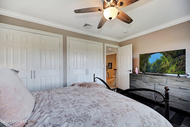 bedroom featuring ceiling fan, two closets, visible vents, and crown molding