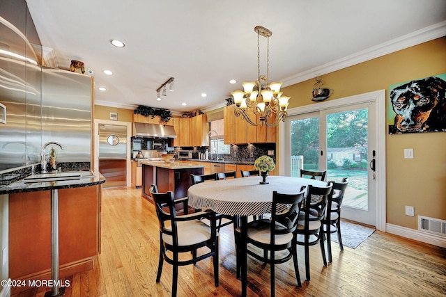 dining area with baseboards, visible vents, light wood-style flooring, an inviting chandelier, and crown molding