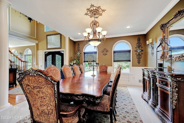 dining room featuring a chandelier, french doors, ornamental molding, wainscoting, and decorative columns