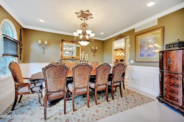 dining room with a wainscoted wall, visible vents, a chandelier, and ornamental molding