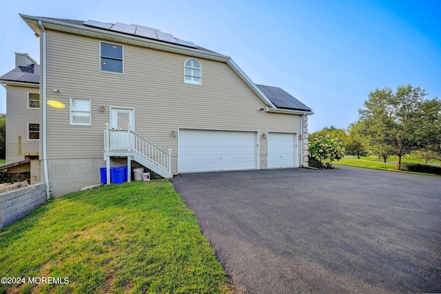 view of front facade with driveway, solar panels, and a front yard