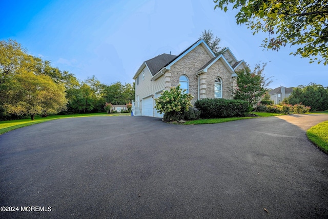 view of front facade with a garage, stone siding, and aphalt driveway