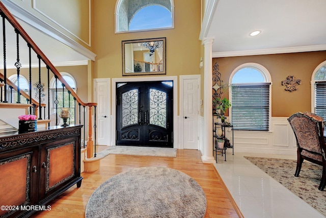 entryway with decorative columns, crown molding, and wood finished floors