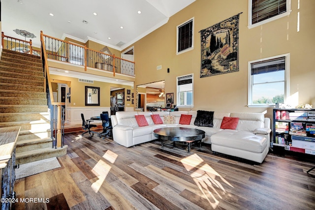 living area with stairway, wood finished floors, a wealth of natural light, and crown molding