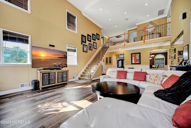 living room featuring a high ceiling, stairs, visible vents, and ornamental molding