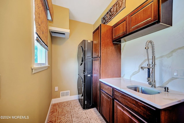 kitchen with stacked washer and dryer, light countertops, visible vents, a sink, and baseboards