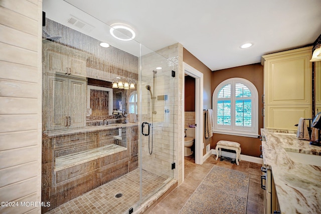 bathroom with toilet, a shower stall, visible vents, and baseboards