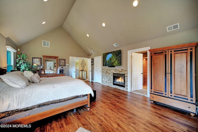 bedroom featuring visible vents, wood finished floors, and a glass covered fireplace