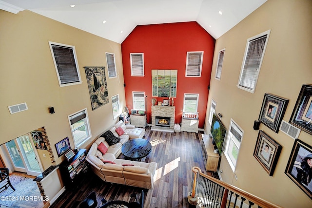 living area featuring high vaulted ceiling, visible vents, a stone fireplace, and wood finished floors