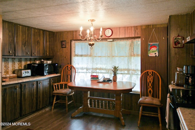 dining space with a textured ceiling, wooden walls, a chandelier, and dark hardwood / wood-style flooring